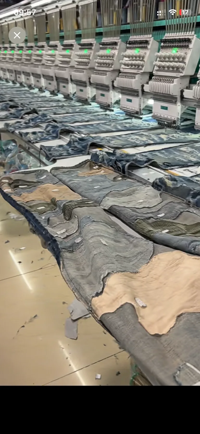 Cut denim garment panels arranged beneath embroidery machine heads