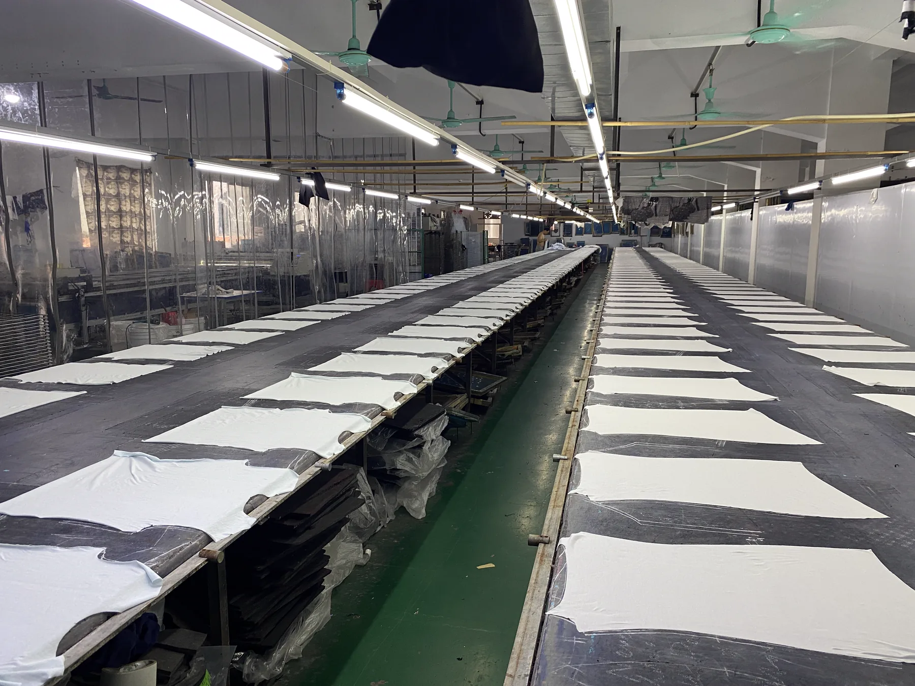 Garment panels arranged across multiple long printing tables