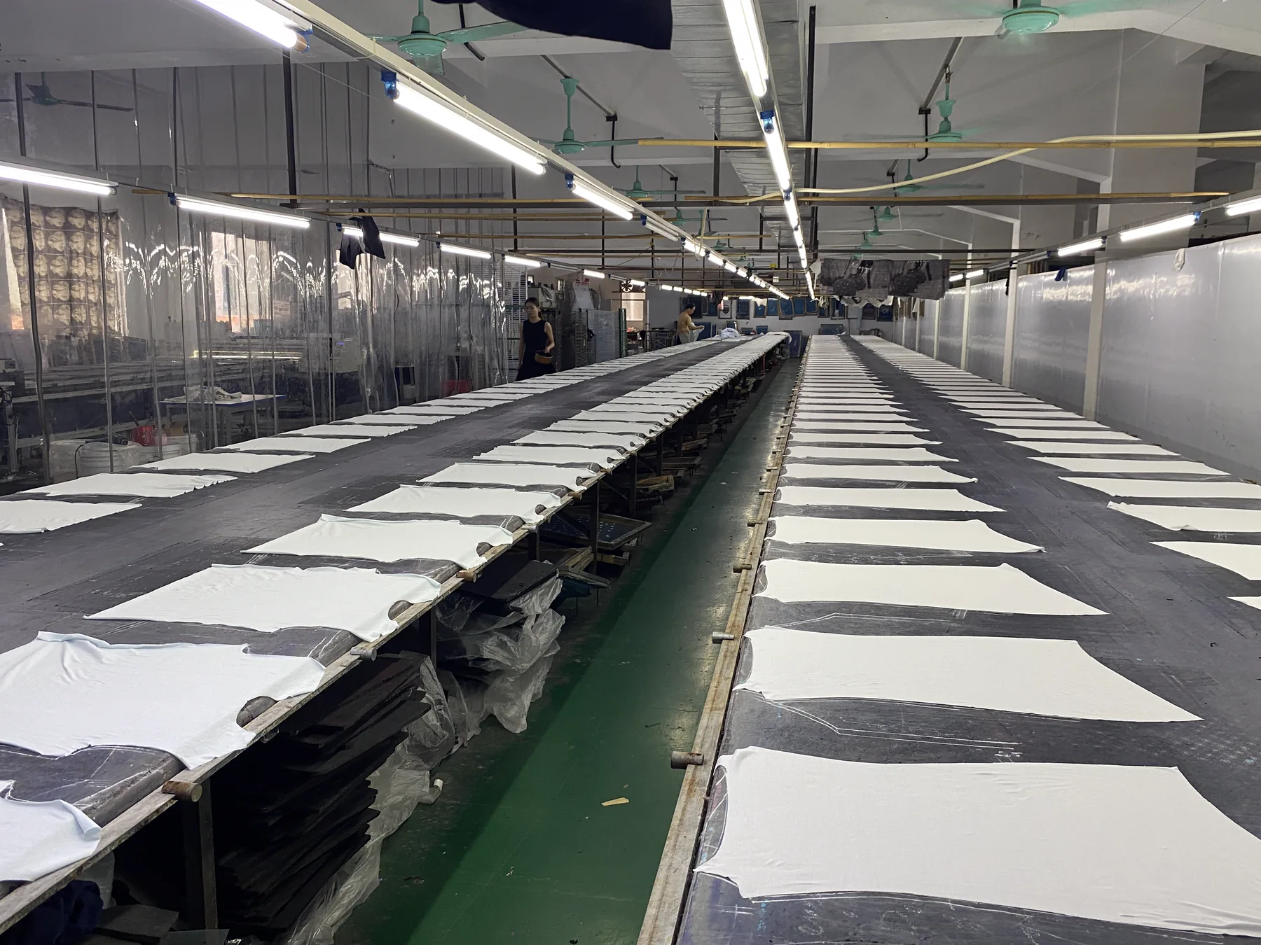 Aligned garment panels across long production tables in the printing workshop