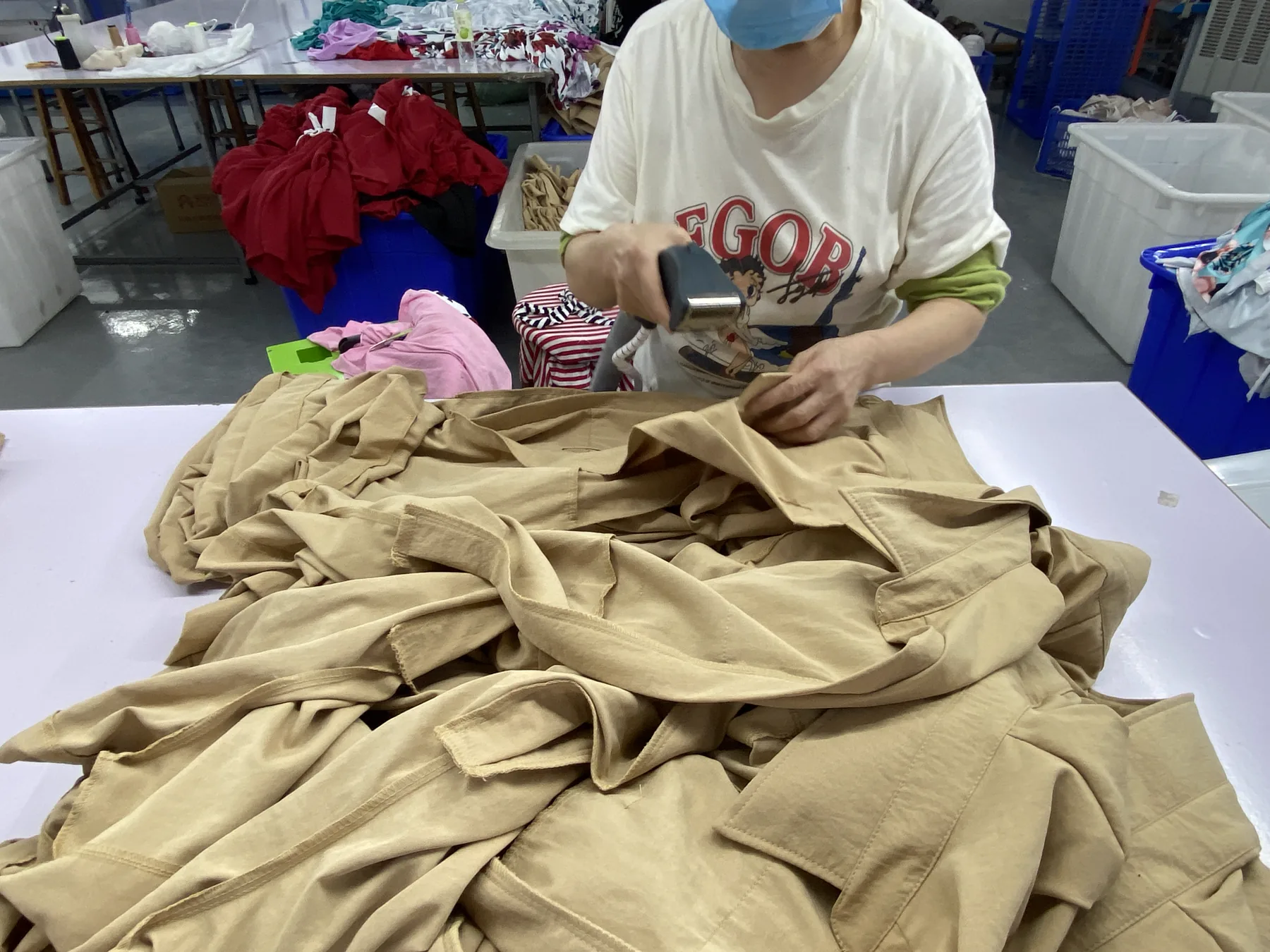 Operator using a handheld steamer while checking finished garments